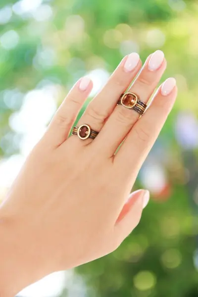 Beautiful women\'s jewelry gold rings with precious stones on an elegant female hand