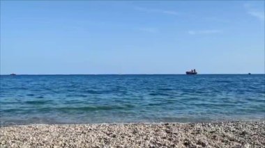 Güzel mavi bir Akdeniz. Kayalık bir kıyısı ve ufukta gemileri var.