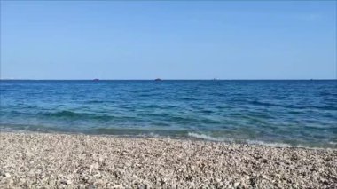 Güzel mavi bir Akdeniz. Kayalık bir kıyısı ve ufukta gemileri var.