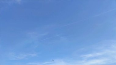 Mavi gökyüzünde bir savaş uçağı uçuyor.