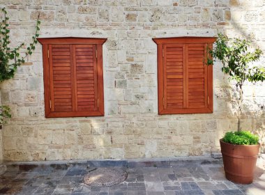 Eski bir evin taş cephesinde çerçevelenmiş pencereler