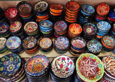 Mağaza vitrininde, çeşitli renklerde geleneksel Doğu Arapça süslemeleri olan yuvarlak tabaklar.