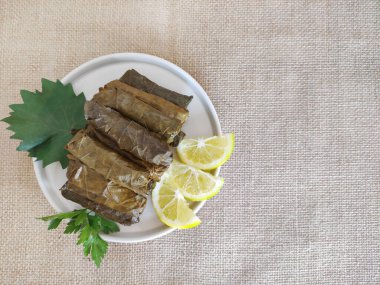 Traditional oriental Turkish dolma made of grape leaves stuffed with rice on a decorative plate clipart
