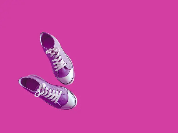 stock image Sporty purple sneakers with white laces on a pink background