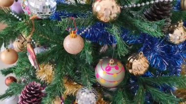 Renkli yeni yıl balonları, oyuncaklar ve yeşil bir Noel ağacının dallarında parlayan çelenkler.