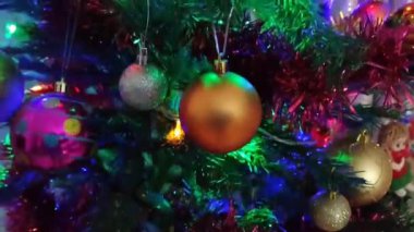 Renkli yeni yıl balonları, oyuncaklar ve yeşil bir Noel ağacının dallarında parlayan çelenkler.