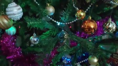 Renkli yeni yıl balonları, oyuncaklar ve yeşil bir Noel ağacının dallarında parlayan çelenkler.