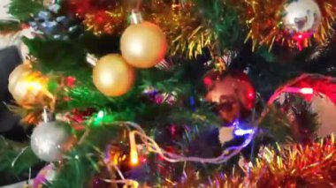 Renkli yeni yıl balonları, oyuncaklar ve yeşil bir Noel ağacının dallarında parlayan çelenkler.