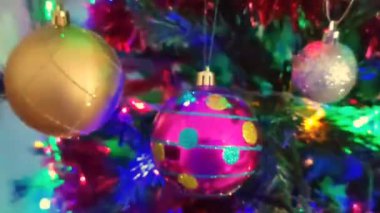 Renkli yeni yıl balonları, oyuncaklar ve yeşil bir Noel ağacının dallarında parlayan çelenkler.