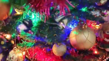 Renkli yeni yıl balonları, oyuncaklar ve yeşil bir Noel ağacının dallarında parlayan çelenkler.