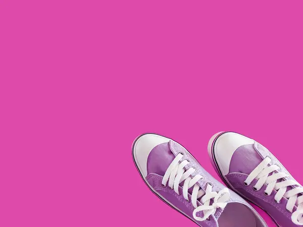 stock image Sporty purple sneakers with white laces on a pink background