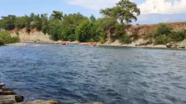 Rafting teknelerindeki insanlar nehir boyunca hızlı bir akıntıyla yol alıyorlar.