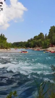 Rafting teknelerindeki insanlar nehir boyunca hızlı bir akıntıyla yol alıyorlar.