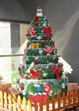 Renkli yılbaşı topları ve fiyonklarla süslenmiş yeşil lastik araba tekerleklerinden yapılmış orijinal bir Noel ağacı.