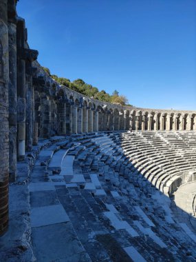 Roma döneminin eski bir harabe amfitiyatrosu. Taş duvarları, kolonları, kemerleri ve merdivenleri var.