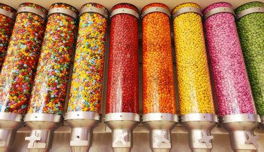 Vitrindeki cam kavanozlarla kaplanmış küçük yuvarlak şekerler.