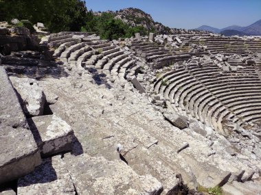 Roma döneminin eski bir harabe amfitiyatrosu. Taş duvarları, kolonları, kemerleri ve merdivenleri var.