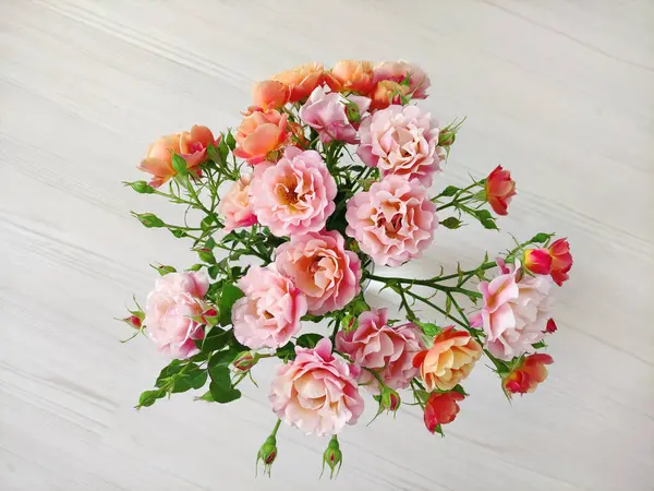 Açık arkaplanda pembe ve turuncu güllerden oluşan güzel bir buket.