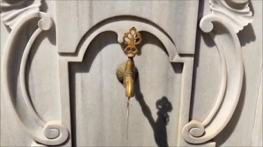 Mermer bir duvardaki dekoratif metal musluk, doğulu Osmanlı tarzında, oyma saplı ve bronz kaplamalı.