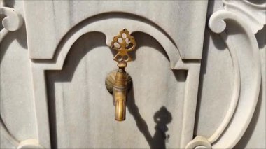 Mermer bir duvardaki dekoratif metal musluk, doğulu Osmanlı tarzında, oyma saplı ve bronz kaplamalı.