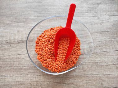 Ahşap bir arka planda dekoratif bir tabakta kurumuş küçük kırmızı mercimek.