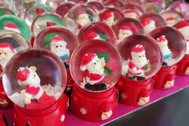 İçinde Noel Baba figürleri olan cam toplar, kırmızı üzerinde kar taneleri ve Noel Baba 'nın küçük resimleriyle süslenmiş.