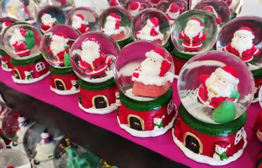 İçinde Noel Baba figürleri olan cam toplar, kırmızı üzerinde kar taneleri ve Noel Baba 'nın küçük resimleriyle süslenmiş.