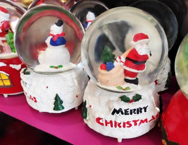 İçinde Noel Baba figürleri olan cam toplar, kırmızı üzerinde kar taneleri ve Noel Baba 'nın küçük resimleriyle süslenmiş.