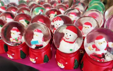 İçinde Noel Baba figürleri olan cam toplar, kırmızı üzerinde kar taneleri ve Noel Baba 'nın küçük resimleriyle süslenmiş.