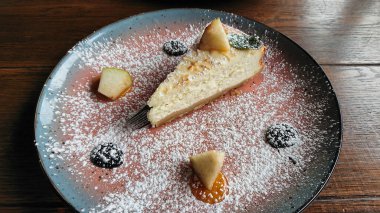 Meyveli peynirli kek dilimi ve tabakta pudra şekeri