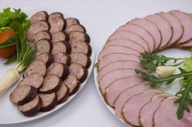 Lezzetli bir çeşit tütsülenmiş sosis ve jambon, iki ayrı tabakta ustalıkla hazırlanmış taze otlar ve tat vermesi için bir diş sarımsak..