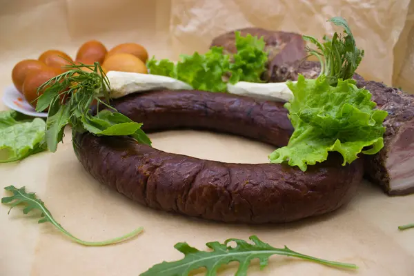 stock image A vibrant display of Easter delicacies, featuring smoked sausage, fresh lettuce, horseradish, and a plate of golden-brown eggs. This composition captures the essence of traditional festive foods, emphasizing natural flavors and fresh ingredients.