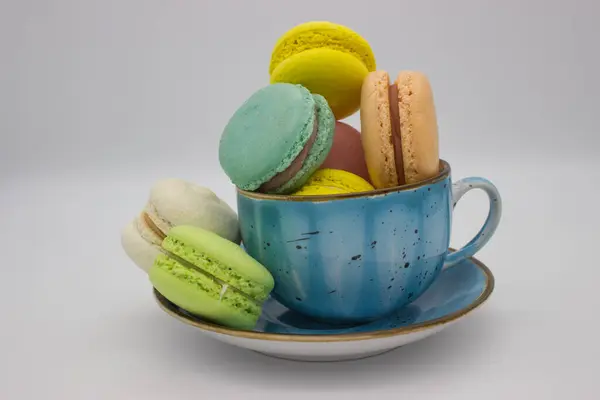 stock image A charming collection of colorful macarons beautifully arranged in a rustic blue cup. Set against a clean white background, this image captures the delightful contrast and elegance of these French treats.