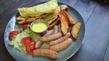 Bir tabakta ızgara sosis ve patates dilimleri.