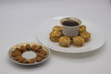 Bir fincan sade kahve, fındık kaplı mini kurabiyeler ve bir tabak bademle şık bir düzen. Sofistike bir kahve molası ya da tatlı zamanı için ideal..