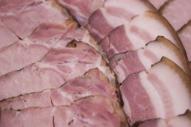 Lezzetli dokularını ve dumanlı aromalarını sergilemek için katmanlı tütsülenmiş sosis ve jambon dilimleri. Şarküteri tabakları veya özel toplantılar için mükemmel..