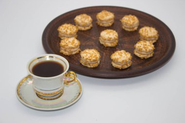 Zarif bir fincan sade kahve ve kremayla dolu mini fındıklı kurabiyeler. Sıcak bir kahve molası ve gurme ikram için mükemmel..