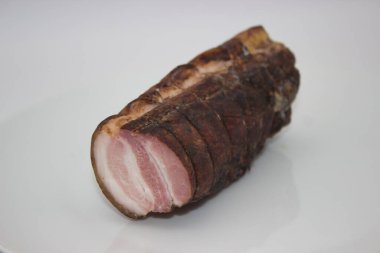 Bu zengin tütsülenmiş domuz filetosu koyu, baharatlı kabuklu ve her dilimin içindeki yumuşak et katmanlarını ortaya çıkaran bir köy cazibesi sunuyor..