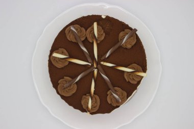 Süslü çikolata kıvrımları ve çizgili çikolata çubuklarıyla kaplı zengin bir çikolatalı pasta. Özel anları kutlamak ya da tatlı menüsünü sergilemek için mükemmel..