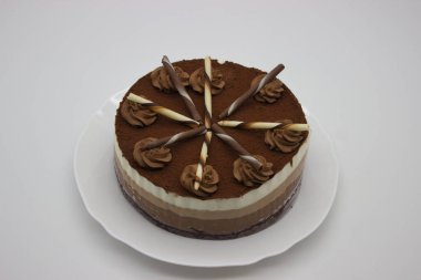Süslü çikolata kıvrımları ve çizgili çikolata çubuklarıyla kaplı zengin bir çikolatalı pasta. Özel anları kutlamak ya da tatlı menüsünü sergilemek için mükemmel..
