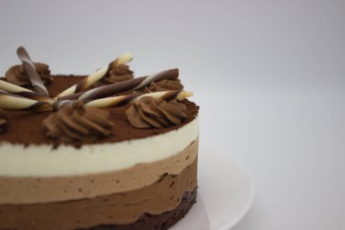 Zengin kakao tozu, dekoratif çikolata ve kremayla kaplı çok katmanlı çikolatalı pastanın yakın görüntüsü. Tatlı meraklıları ve çikolata severler için mükemmel..