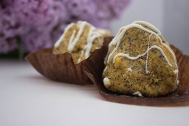 A detailed shot of a homemade poppy seed pastry, topped with a delicate drizzle of white icing. The pastry sits in a brown paper wrapper, creating a warm, inviting presentation. clipart