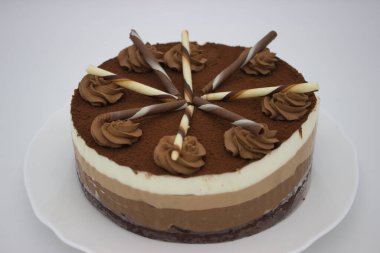 Zengin kakao tozu, dekoratif çikolata ve kremayla kaplı çok katmanlı çikolatalı pastanın yakın görüntüsü. Tatlı meraklıları ve çikolata severler için mükemmel..