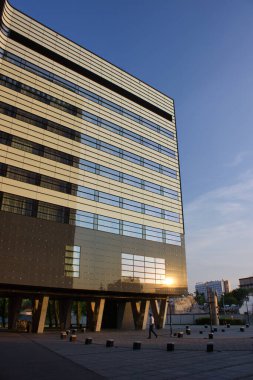 Çağdaş kentsel tasarımı barındıran minimalist cam bina yüksek yapı ve günbatımı yansıması.