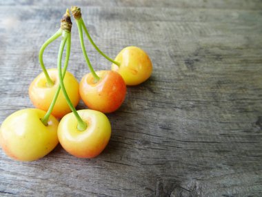 Ahşap arka planda olgun kiraz meyveleri, yakın planda hafif çilekler. Lezzetli kiraz meyveleri