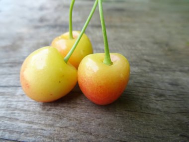 Ahşap arka planda olgun kiraz meyveleri, yakın planda hafif çilekler. Lezzetli kiraz meyveleri