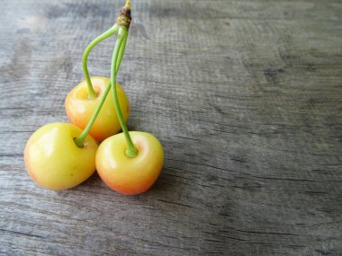Ahşap arka planda olgun kiraz meyveleri, yakın planda hafif çilekler. Lezzetli kiraz meyveleri