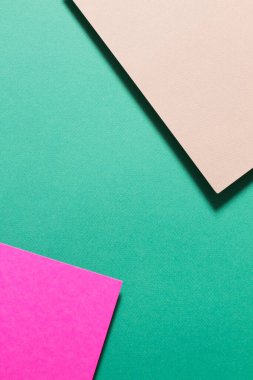 İki renkli mukavvanın geometrik bileşimi ve onların gölgeleri yeşil arka planda.