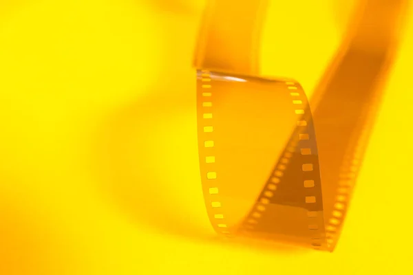 Translucent fragment of 35 mm movie on yellow surface.