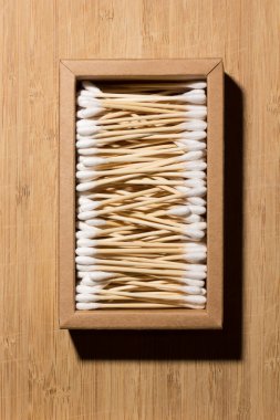 Set of cotton sticks, made of bamboo, inside a cardboard box on a bamboo surface. Non-plastic concept.